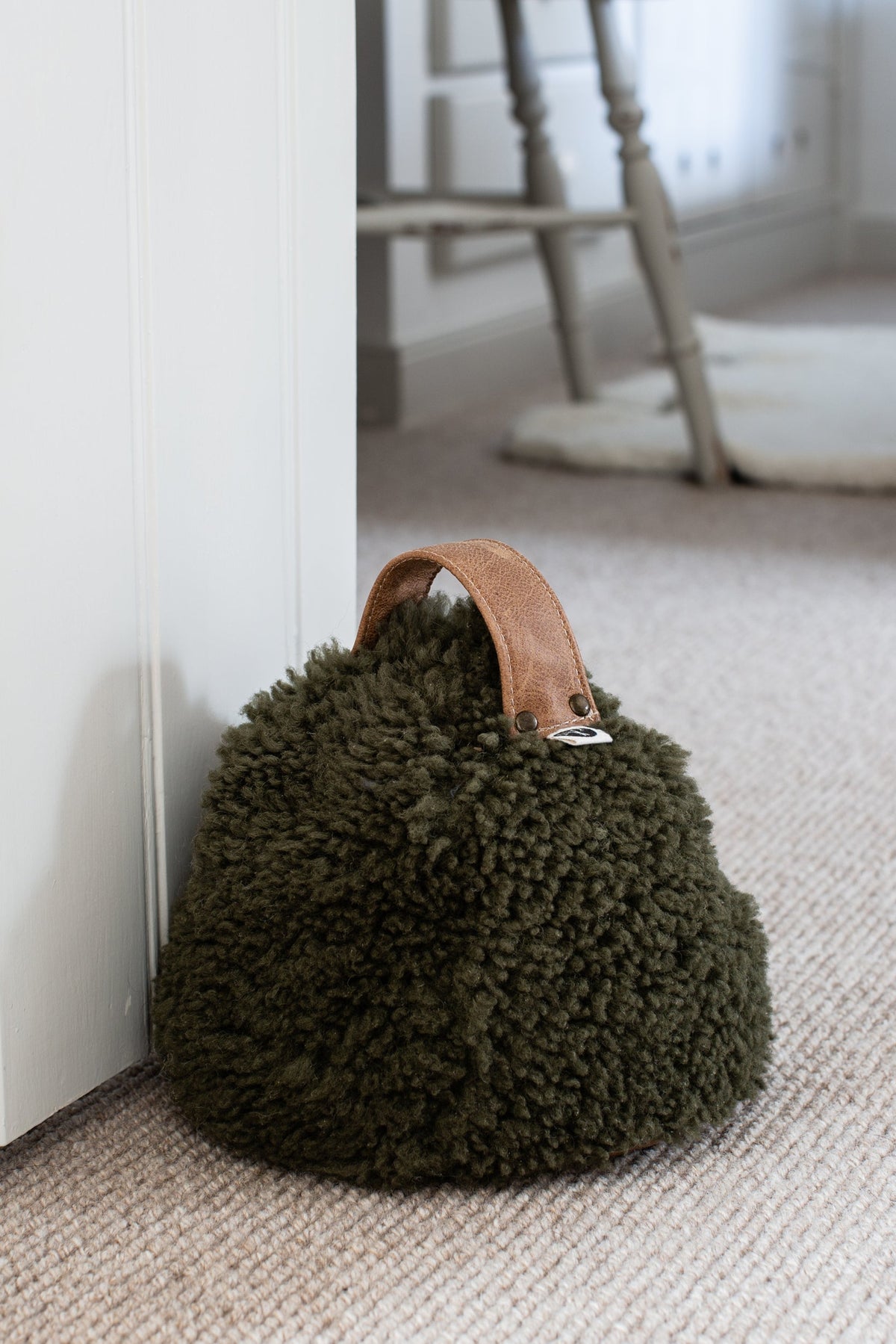 Olive cropped sheepskin door stop with a leather handle