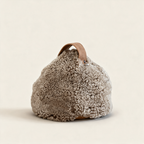 Brown cropped sheepskin door stop with a leather handle, on a cream background