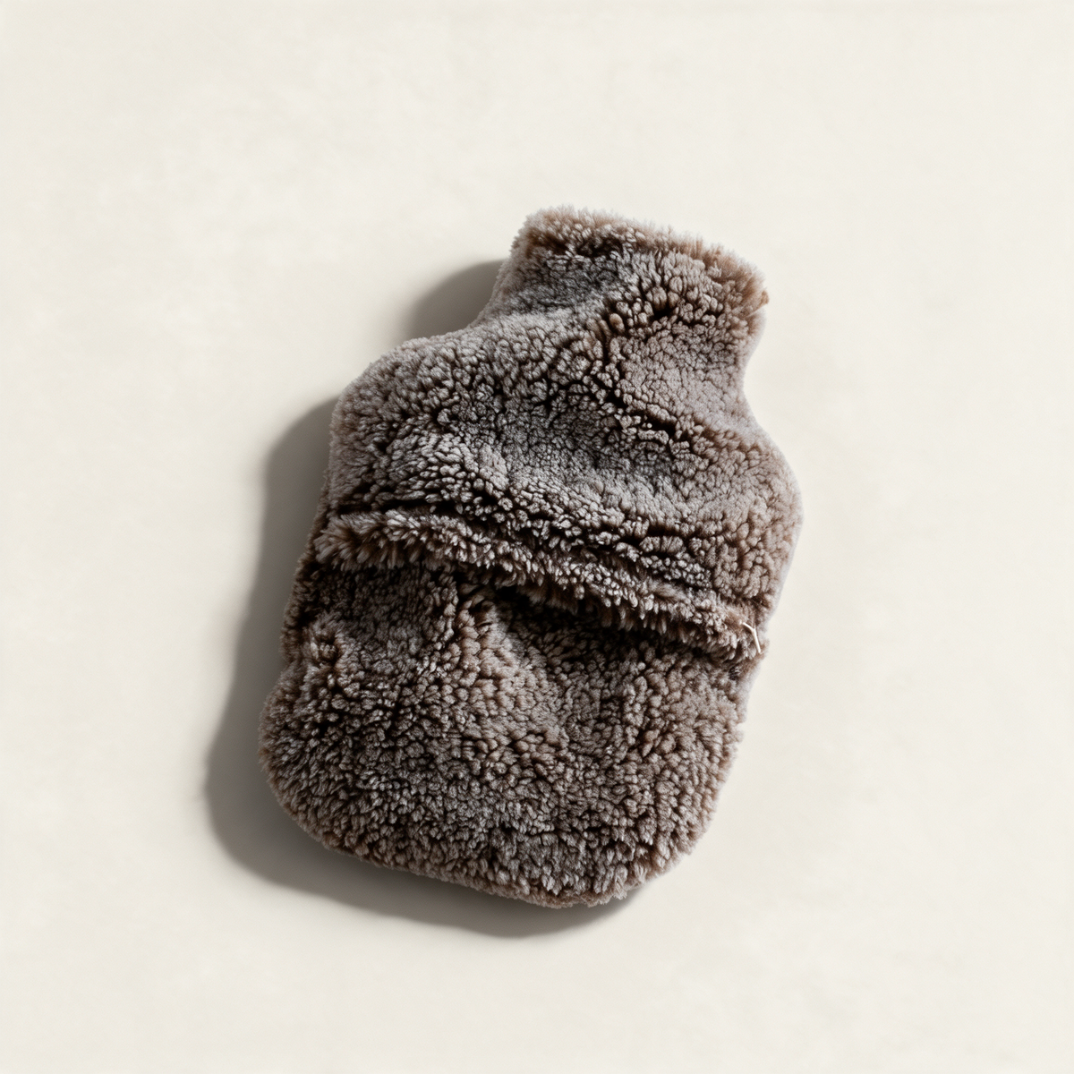Brown teddy sheepskin hot water bottle cover, on a cream background