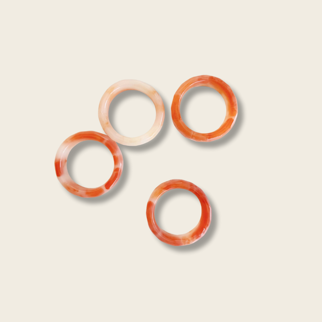four orange napkin rings on a beige background