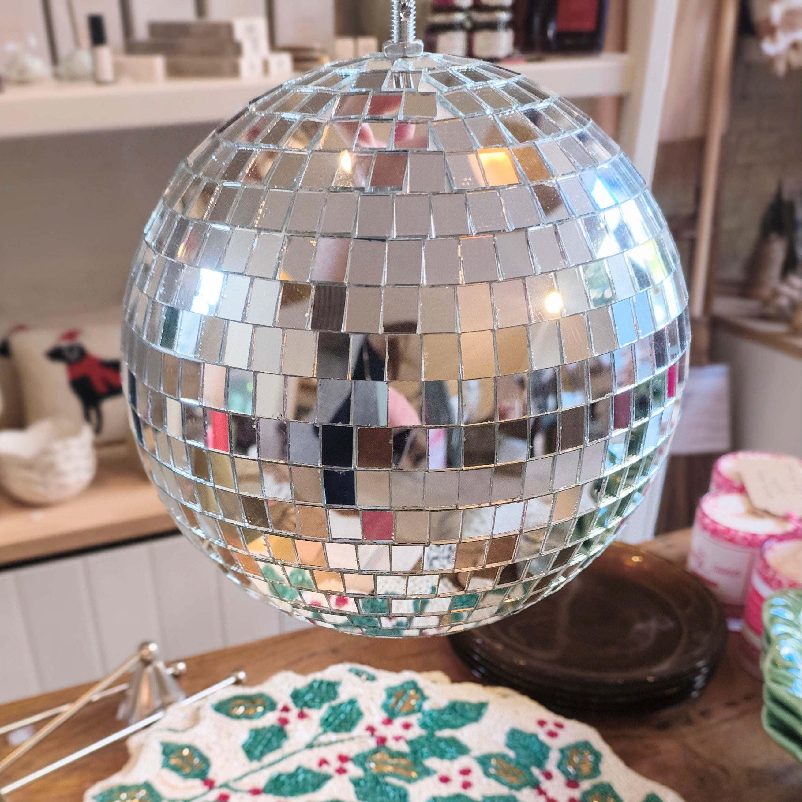 Silver disco ball on a table with a decorative plate featuring holly design.