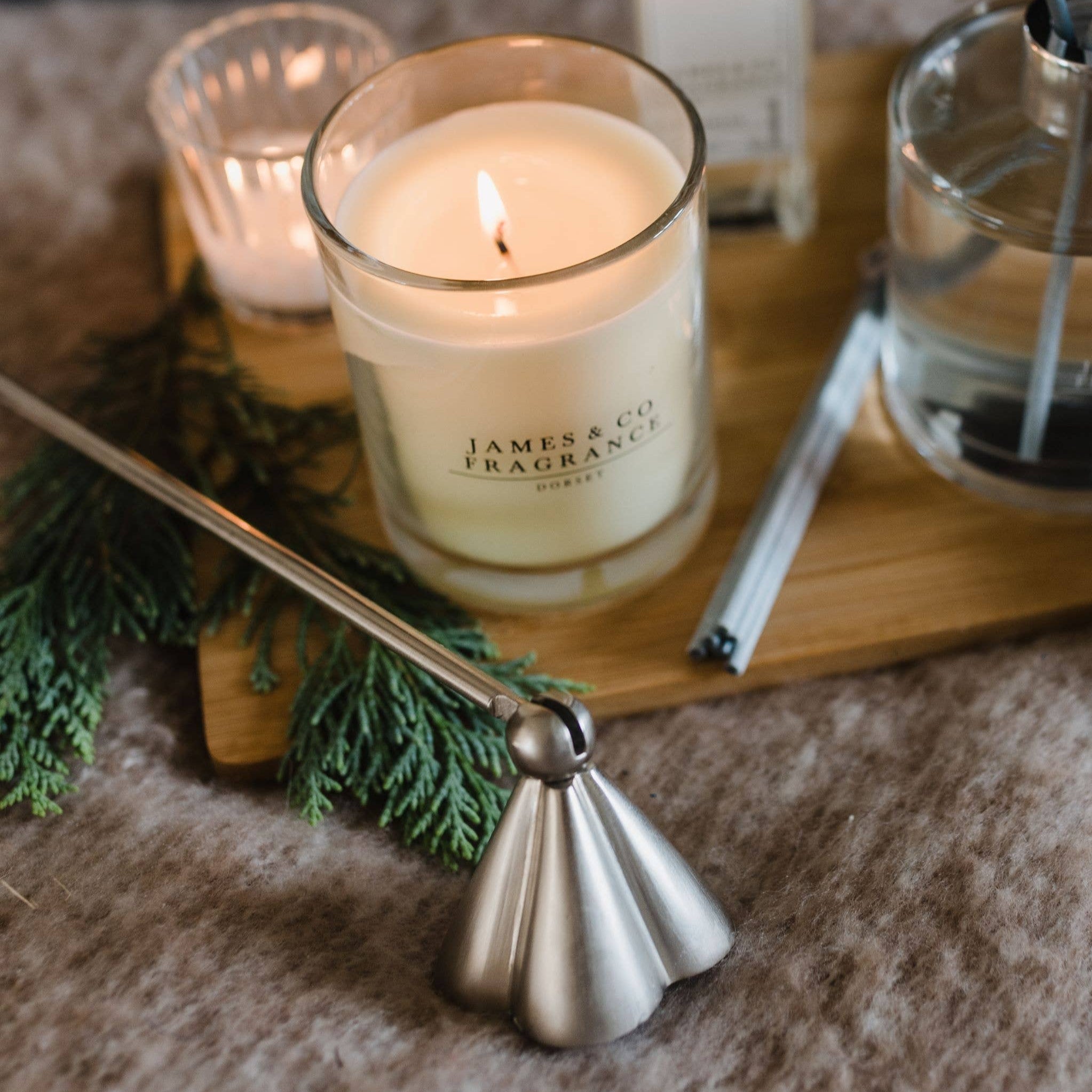Candle, diffuser, and candles on a wooden tray with a fireplace in the background