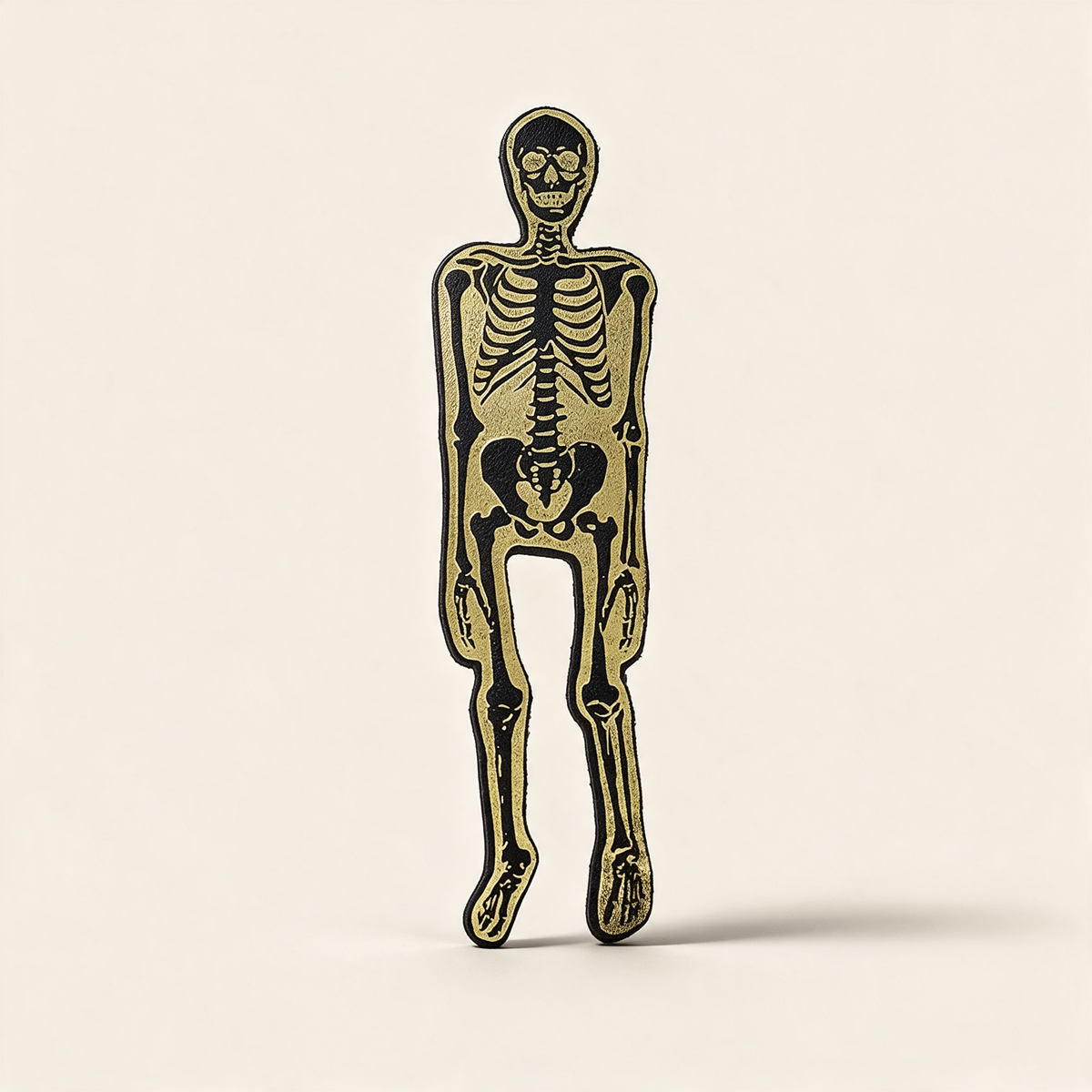 Black leather skeleton bookmark die-cut in a skeleton silhouette, gold foil design, on a cream background