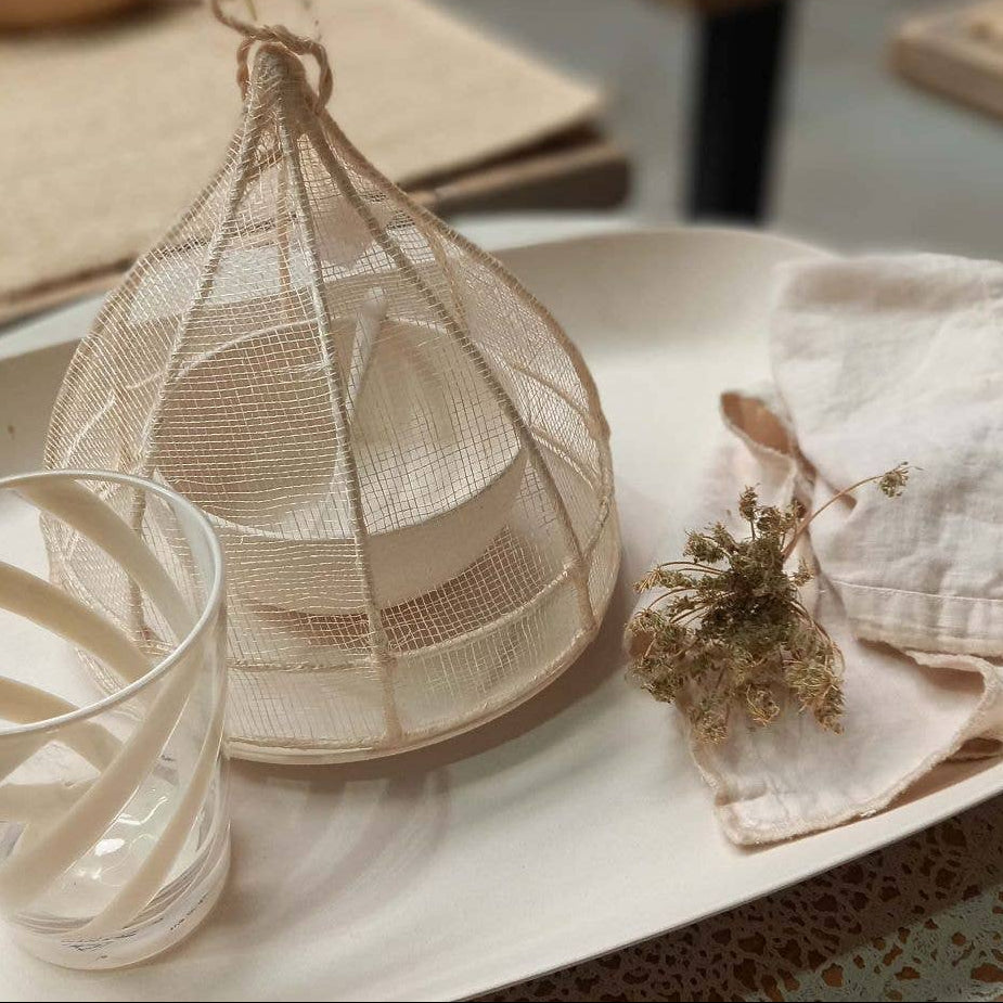Decorative mesh basket on a table with a glass and fabric item, featuring 'fiorir  un giardino' branding.