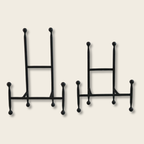 a small and large iron chair style easel on a beige background