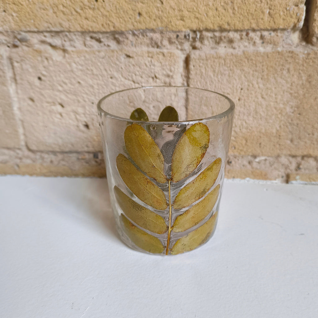 Clear glass with leaf design on a white surface and stone wall background