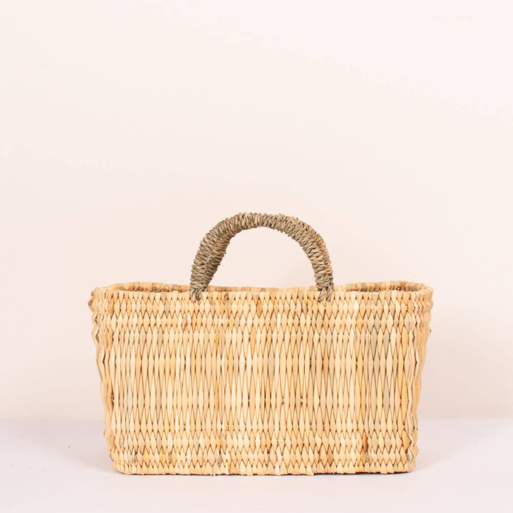Woven basket with handle on a light beige background