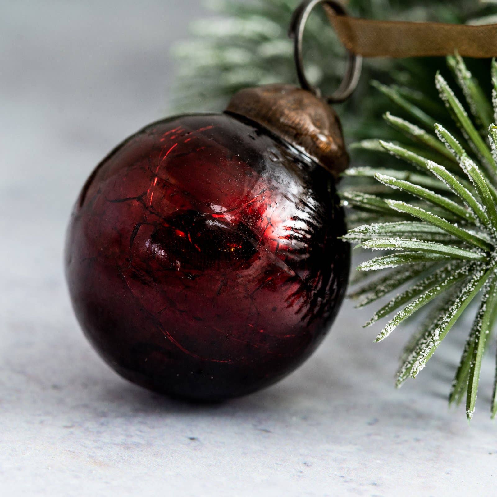Red glass ornament with brown acorn on a branch