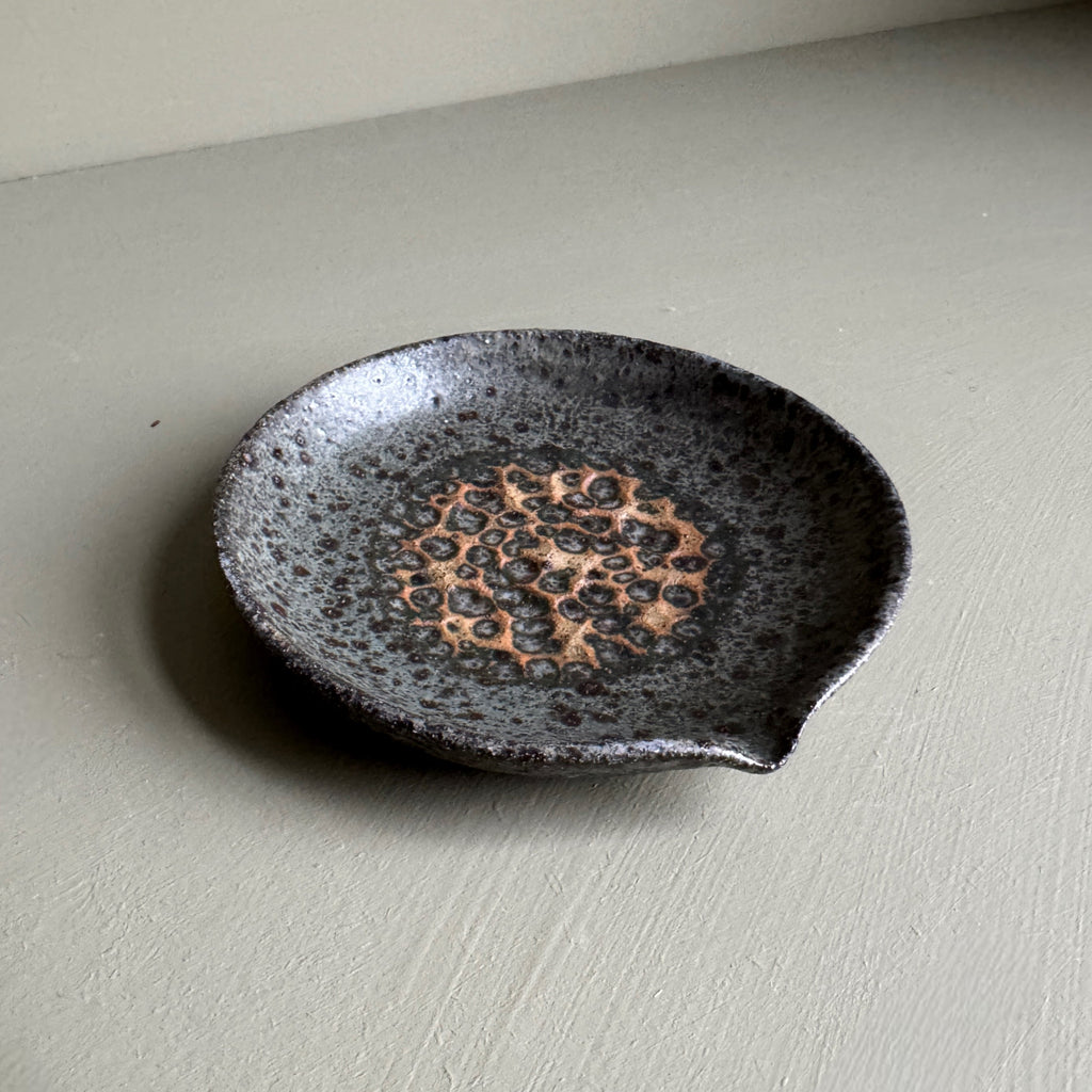 Black ceramic dish with textured design on a light gray surface