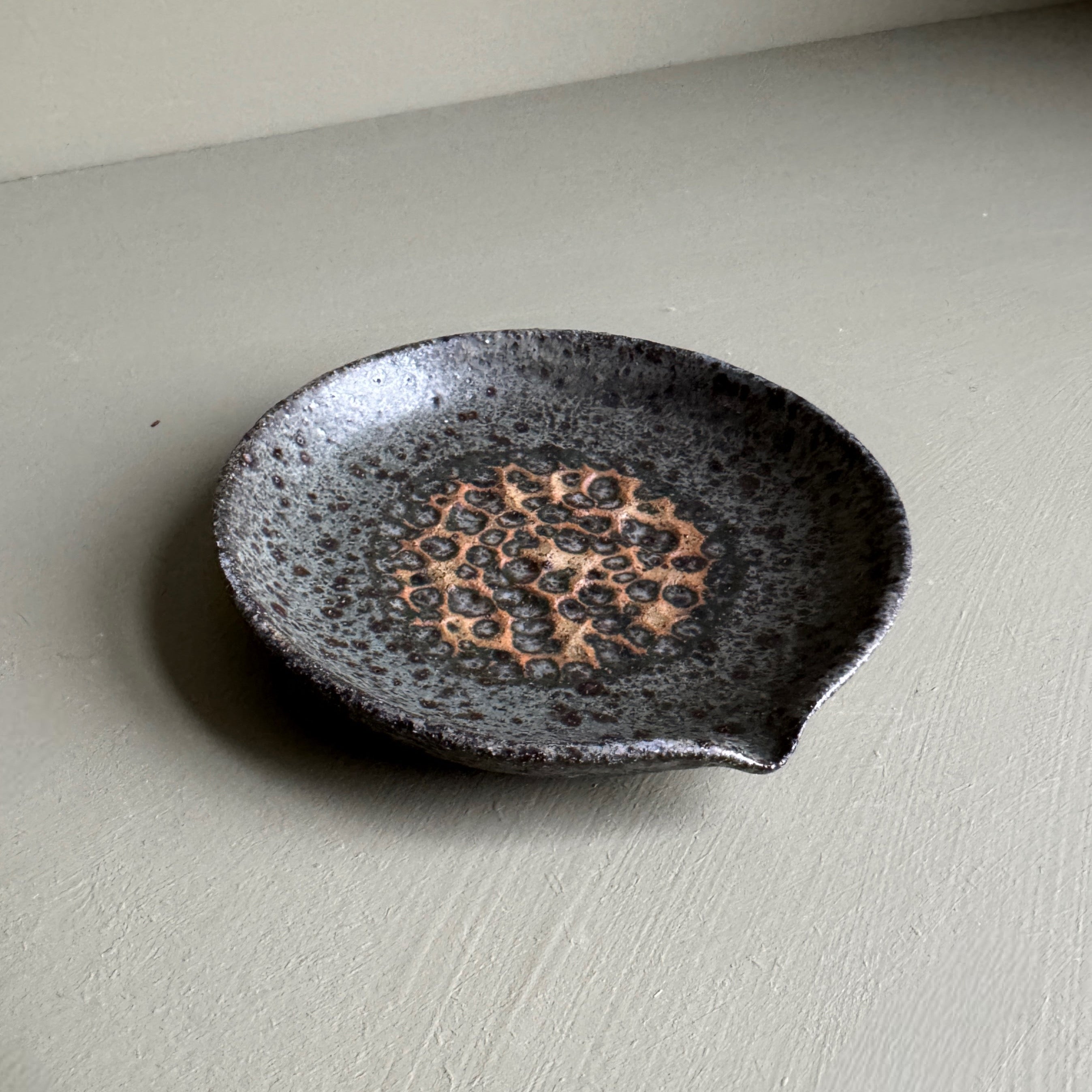 Black ceramic dish with textured design on a light gray surface