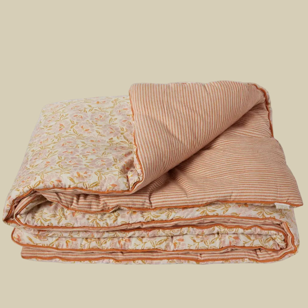 Folded quilt with floral and striped patterns on a white background