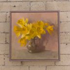Framed painting of yellow flowers on a brick wall