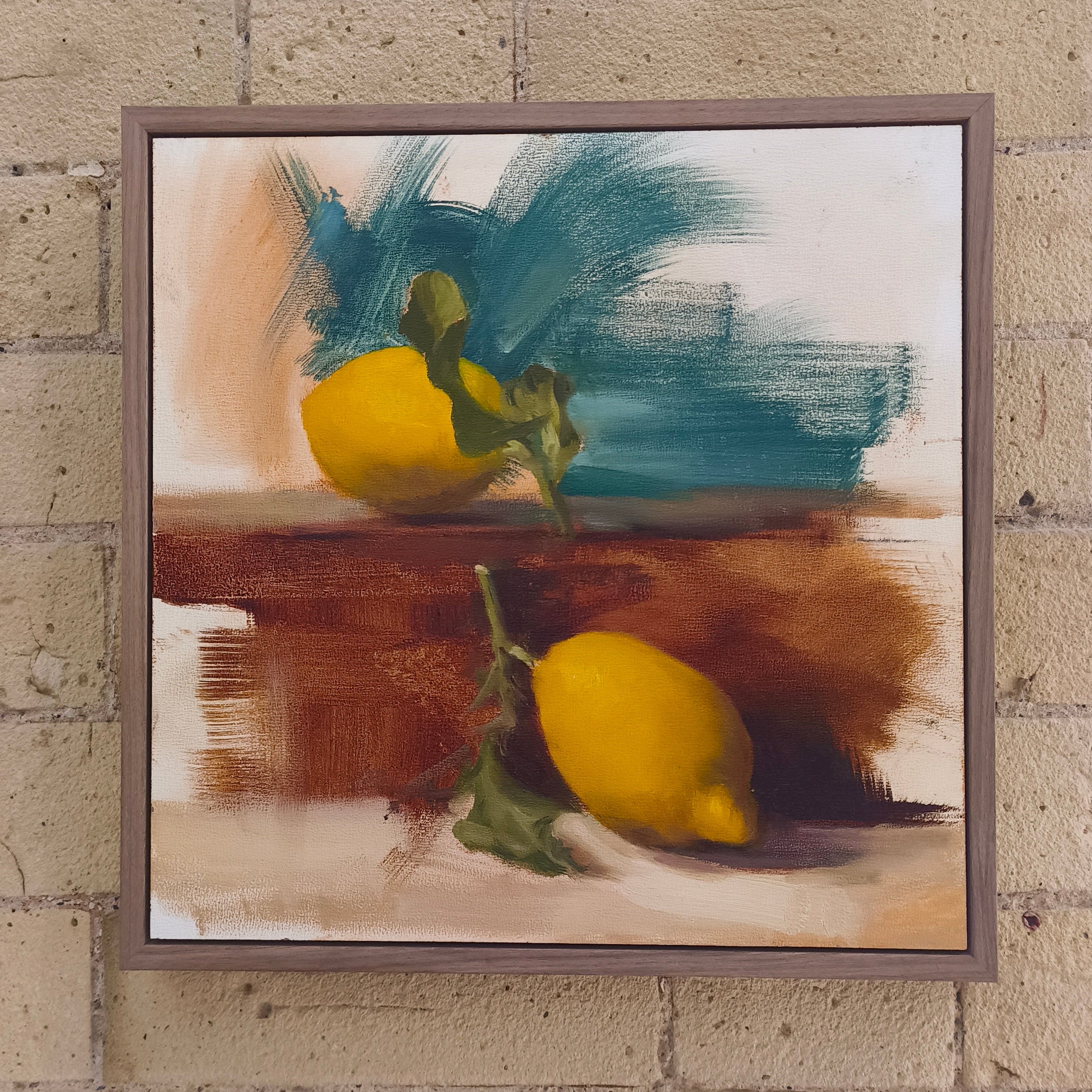 Framed painting of lemons on a textured wall