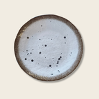 Ceramic plate with speckled design on a beige background
