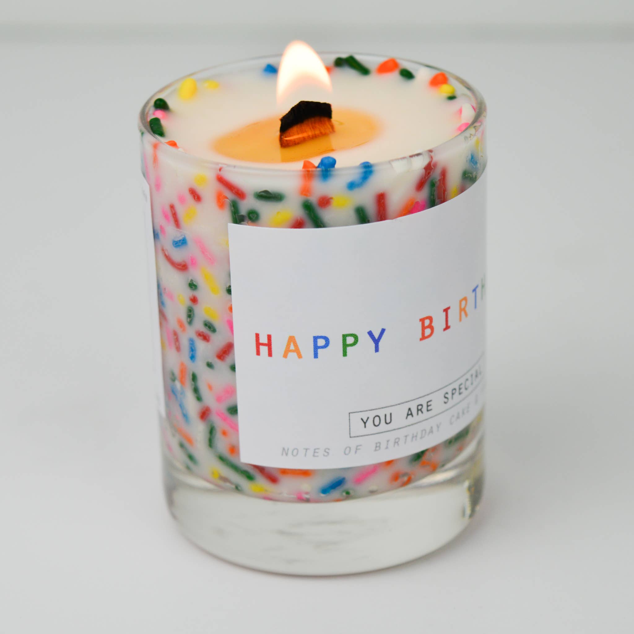 Candle with colorful sprinkles and a 'Happy Birthday' label on a white background
