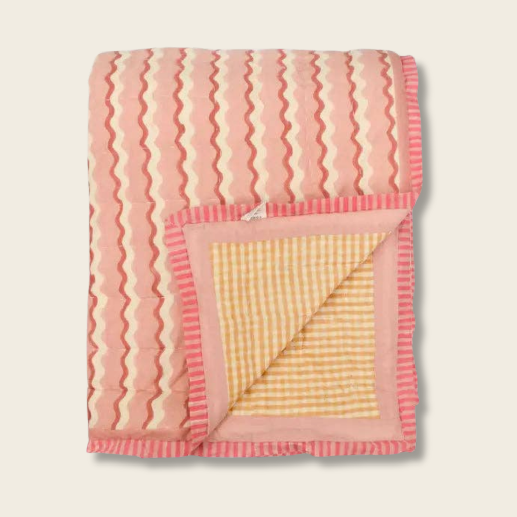 pink blanket with orange and white squiggles with yellow gingham face side. 