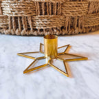 Gold star-shaped candle holder on a marble surface with a woven basket in the background.