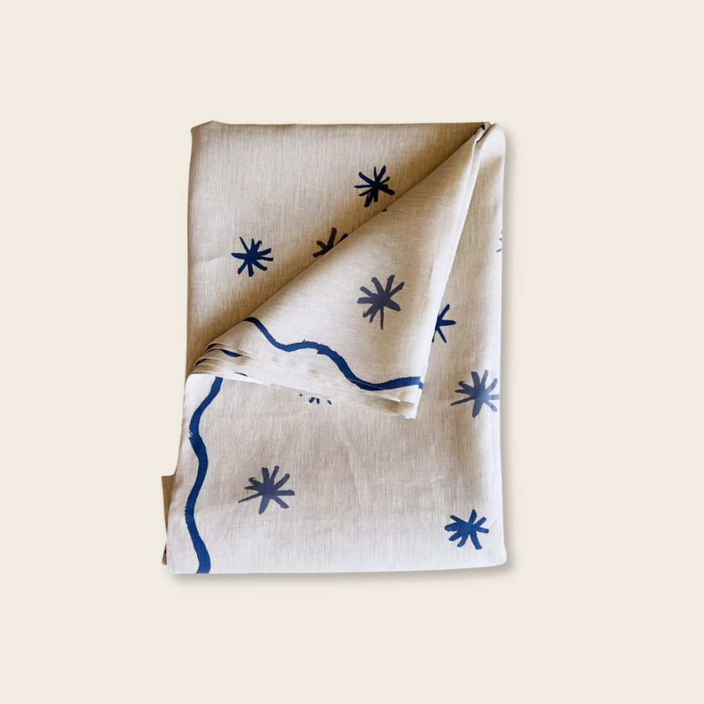 Folded table cloth with blue star and line patterns on a beige background