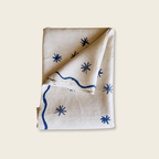 Folded table cloth with blue star and line patterns on a beige background