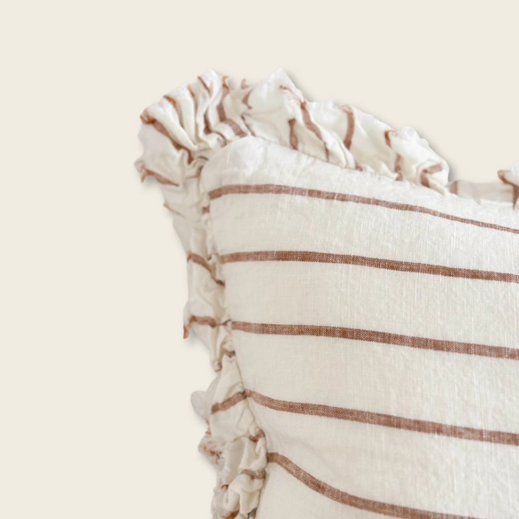 Close-up of a striped fabric with tassels on a beige background