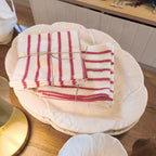 Stack of white plates with a red and white striped cloth on top, placed on a wooden surface.