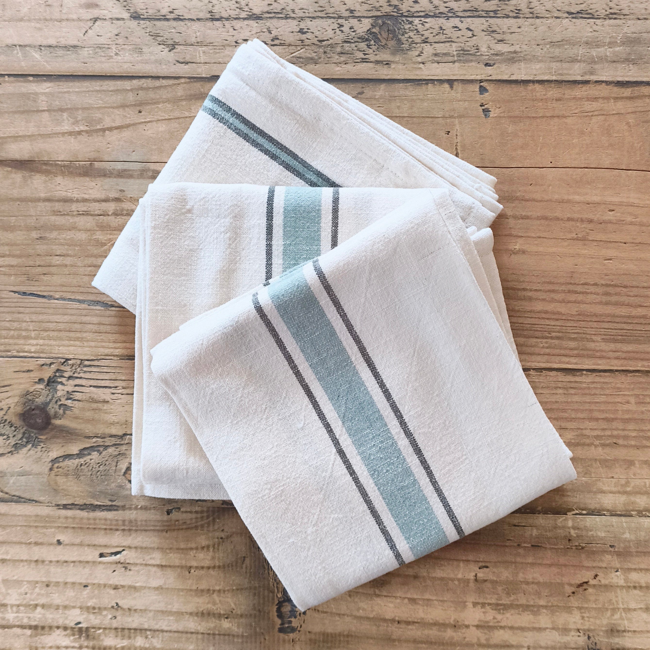 Two folded towels with blue stripes on a wooden surface