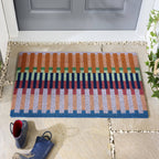 Colorful striped doormat on a stone patio with a gray door in the background.