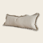 Rectangular pillow with striped pattern and frayed edges on a beige background