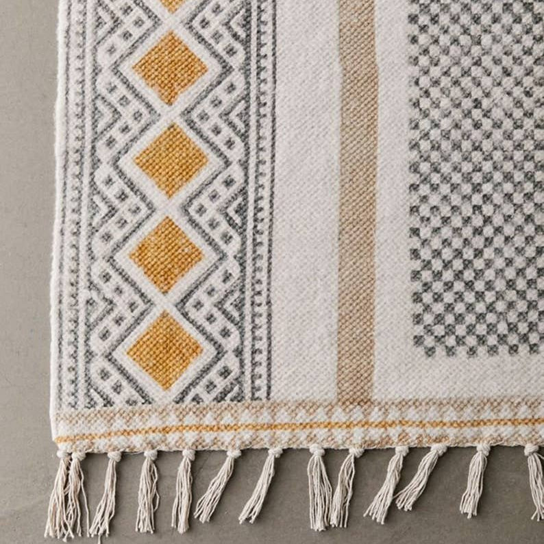Textile with geometric pattern and fringes on a gray background