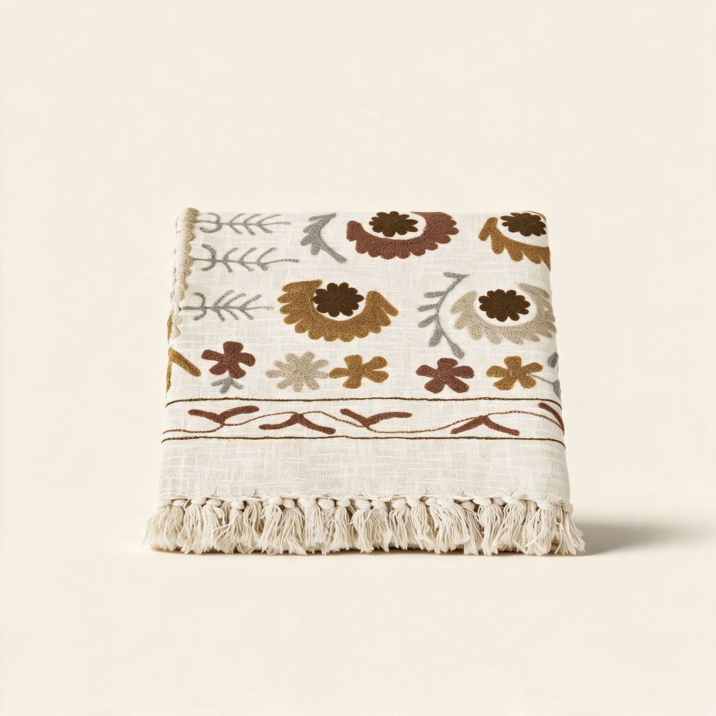 Suzani embroidered cotton throw in off white, grey, brown and tobacco on a warm cream background