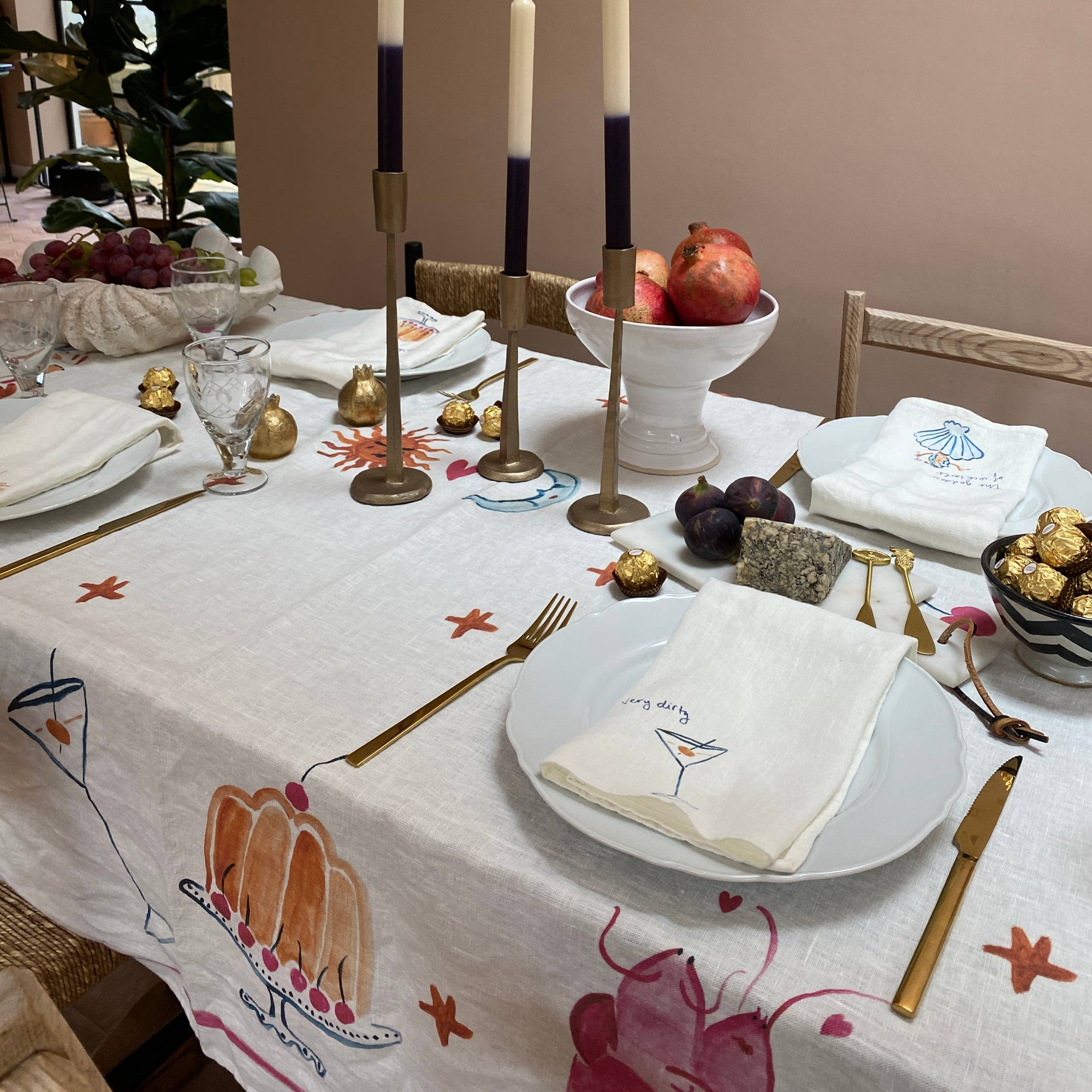 Dining table set with candles, fruit, and decorative items in a home setting.