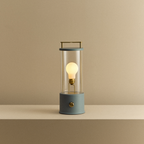 Modern lantern-style lamp with a lit bulb on a beige background