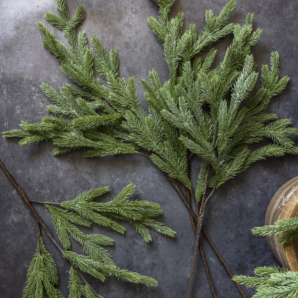 Artificial greenery branches on a dark stone surface