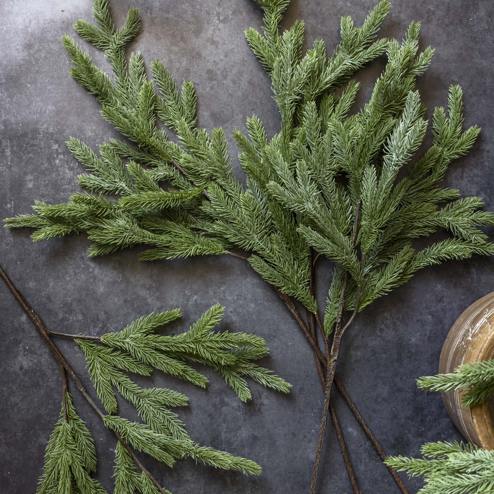 Artificial greenery branches on a dark stone surface