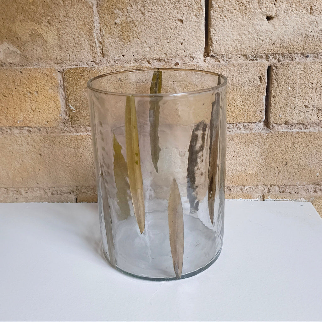 Clear glass vase on a white surface with a brick wall background