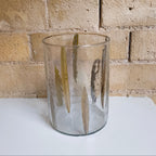 Clear glass vase on a white surface with a brick wall background