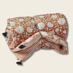 Folded quilt with floral and striped pattern on a beige background