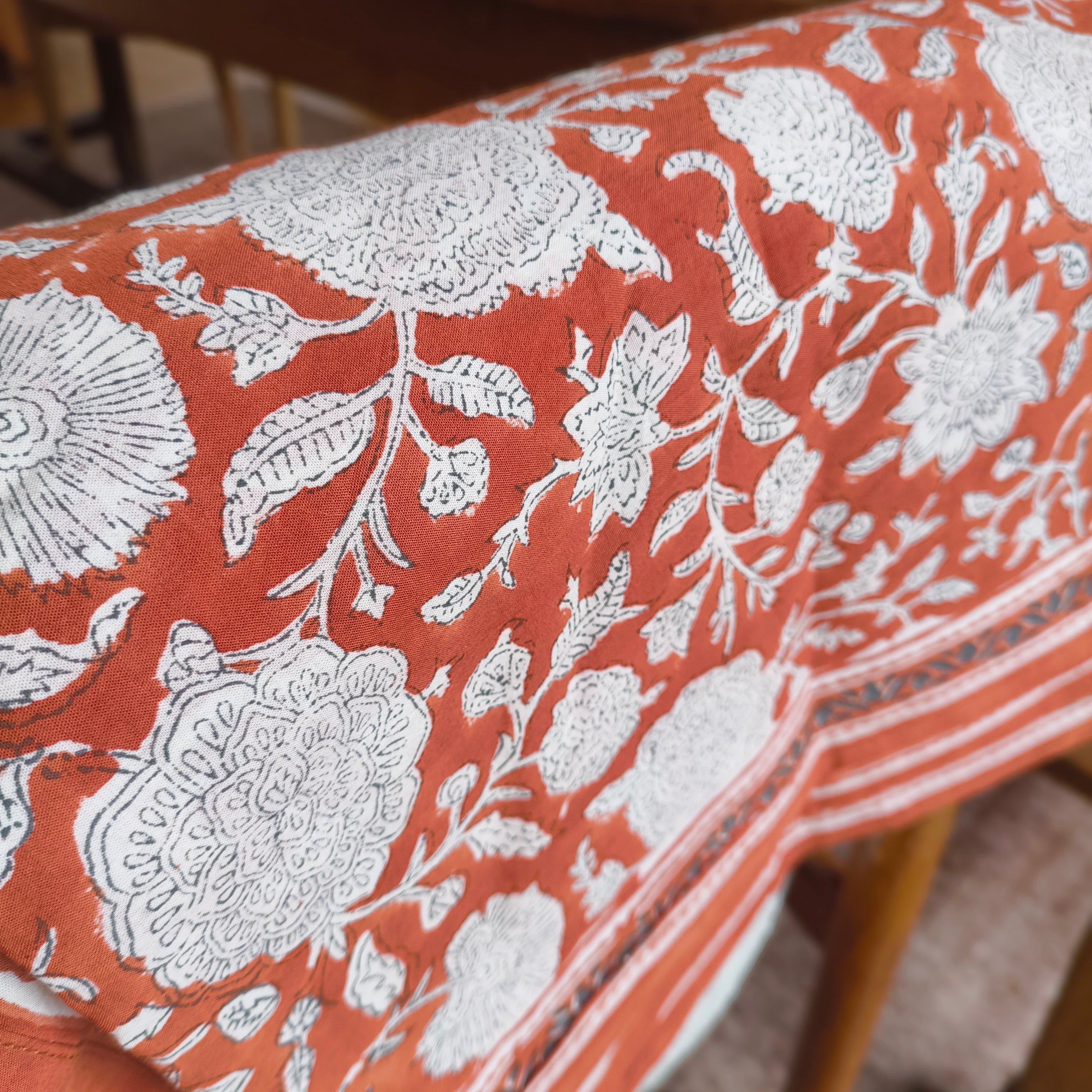 Floral patterned tablecloth on a wooden table with a blurred background