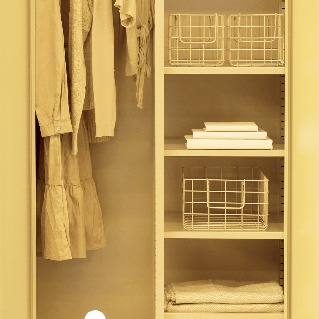 Closet with shelves and wire baskets, containing folded clothes and a jacket.