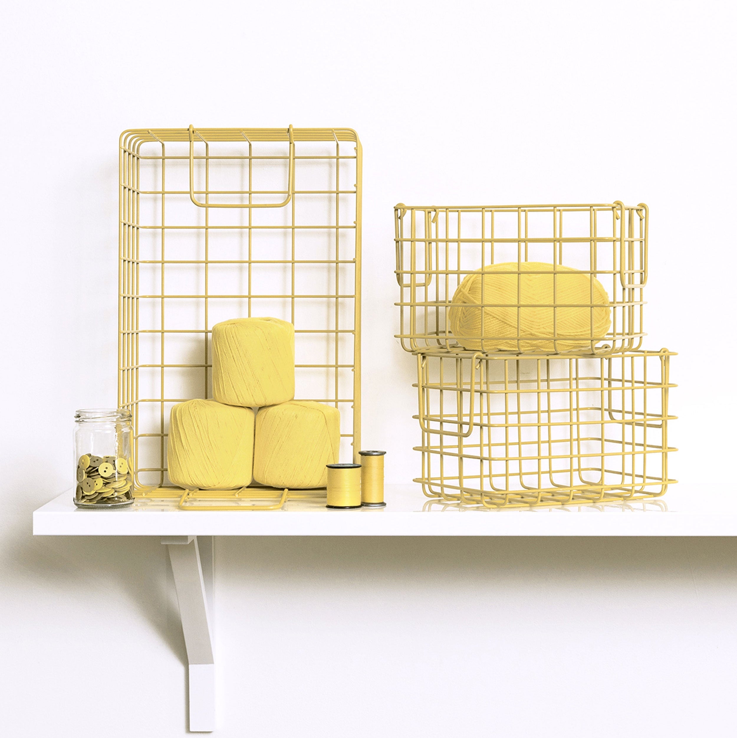Yellow wire baskets on a white shelf with a white background