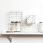 White wire baskets and jars on a white shelf against a white background