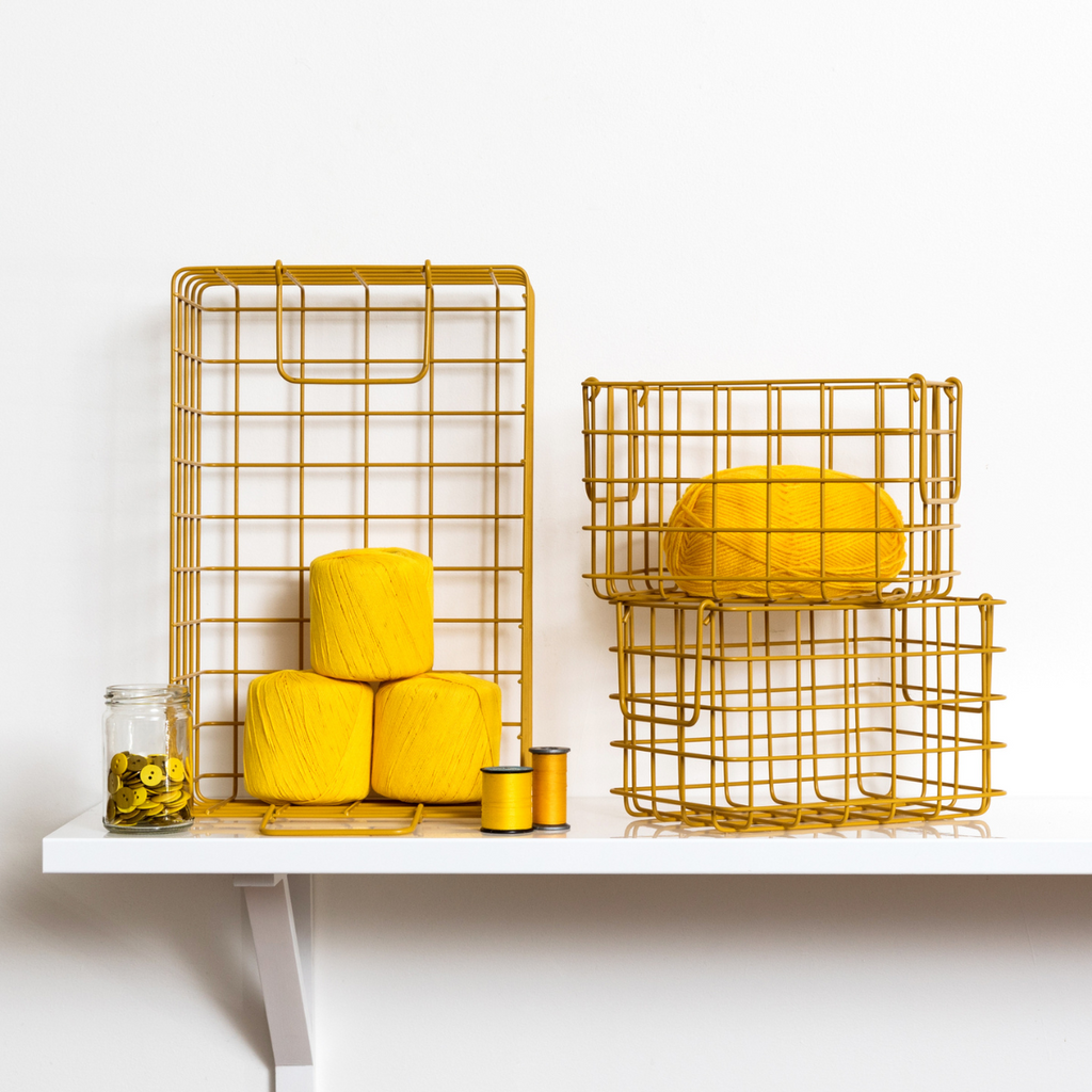 Yellow yarn and baskets on a white shelf against a white wall