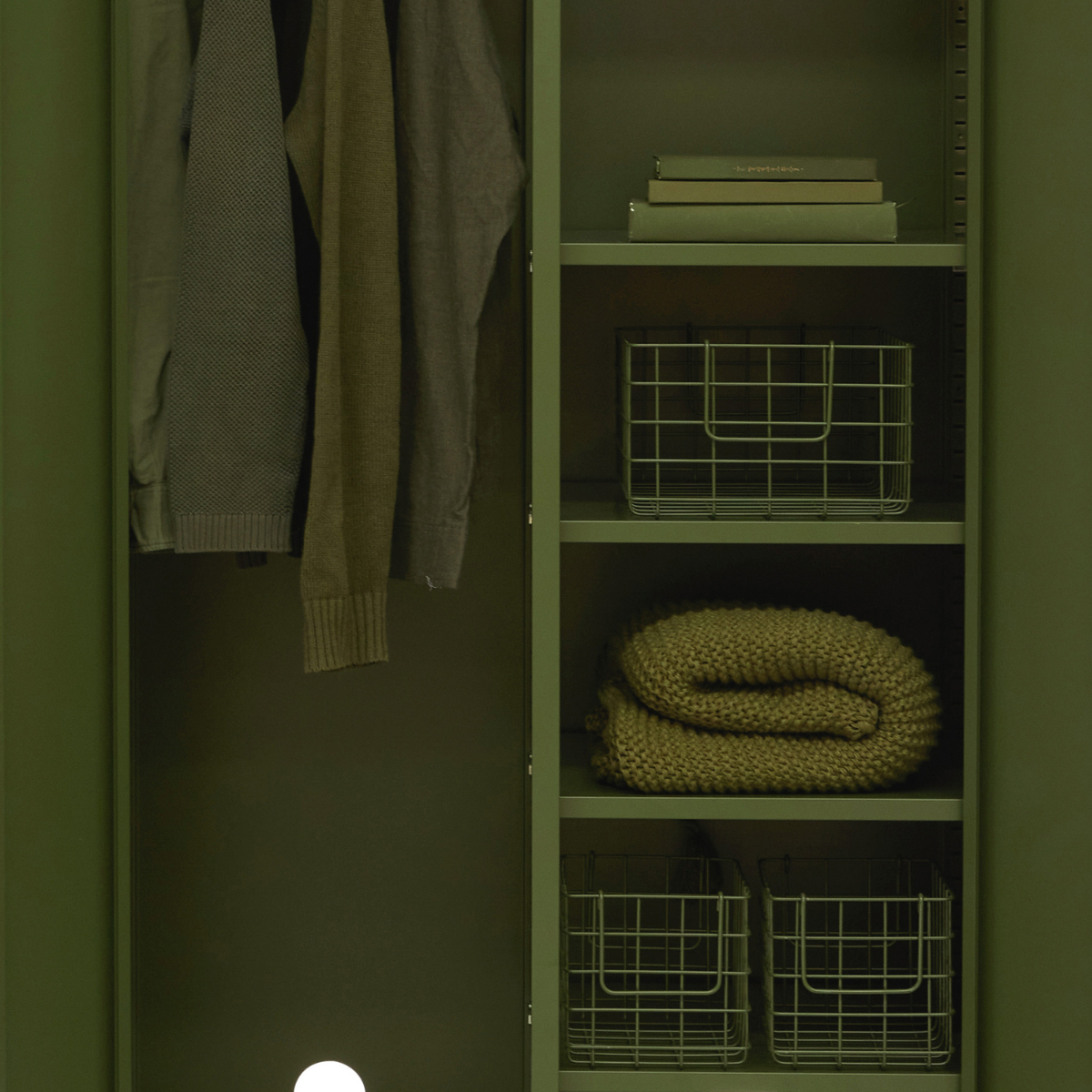 Green wardrobe with clothes and storage baskets inside