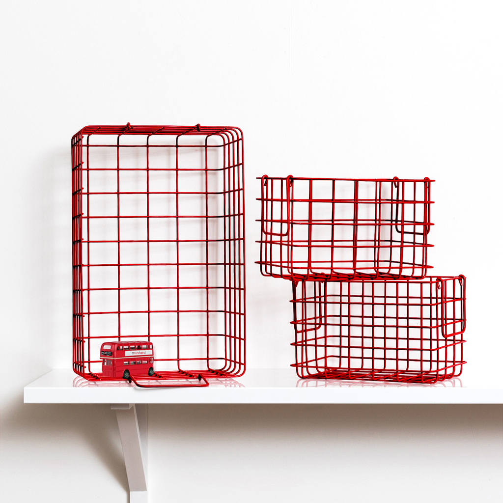 Two red wire baskets on a white shelf with a white background