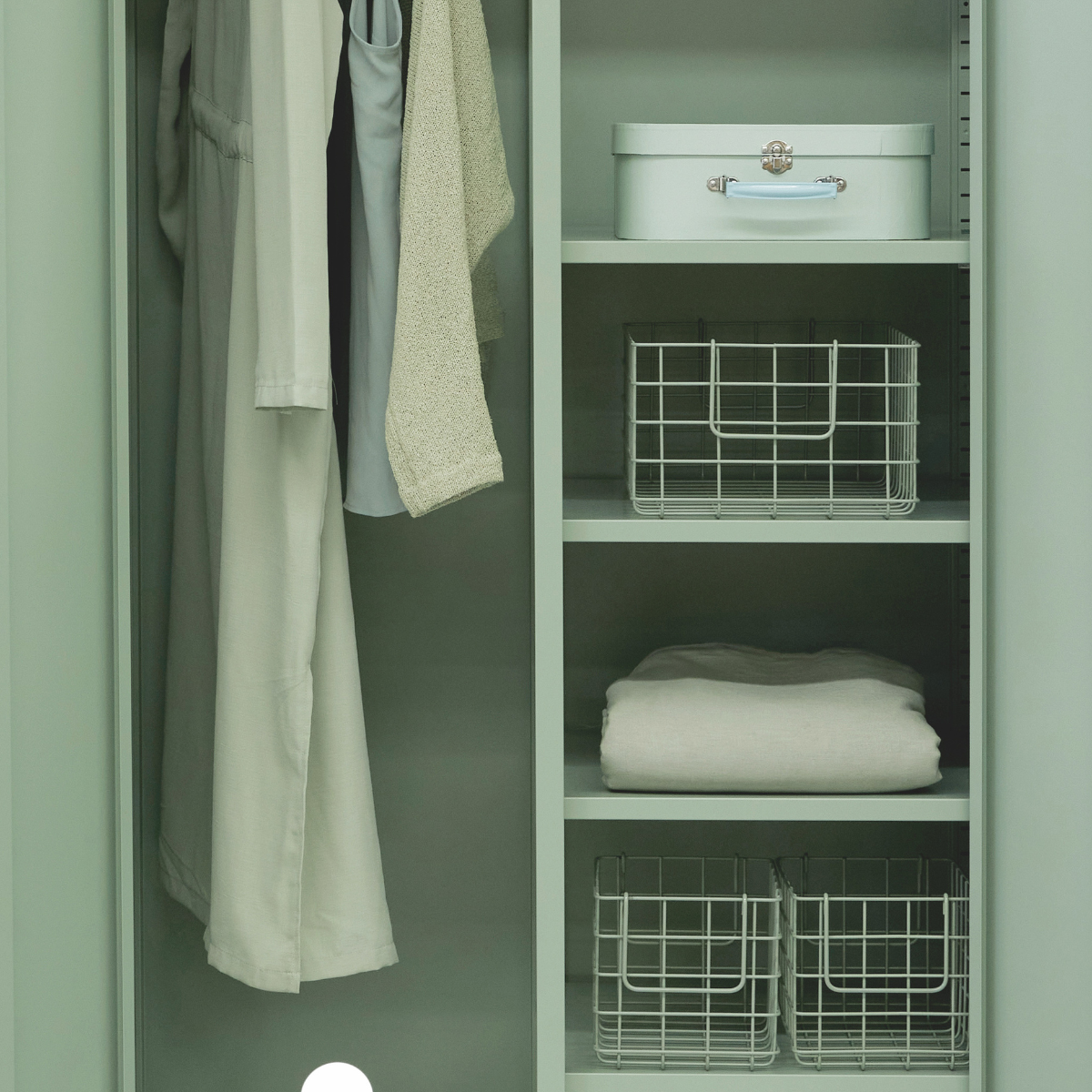 Green wardrobe with clothes and storage baskets