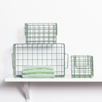 Set of green wire baskets on a white surface with a white background