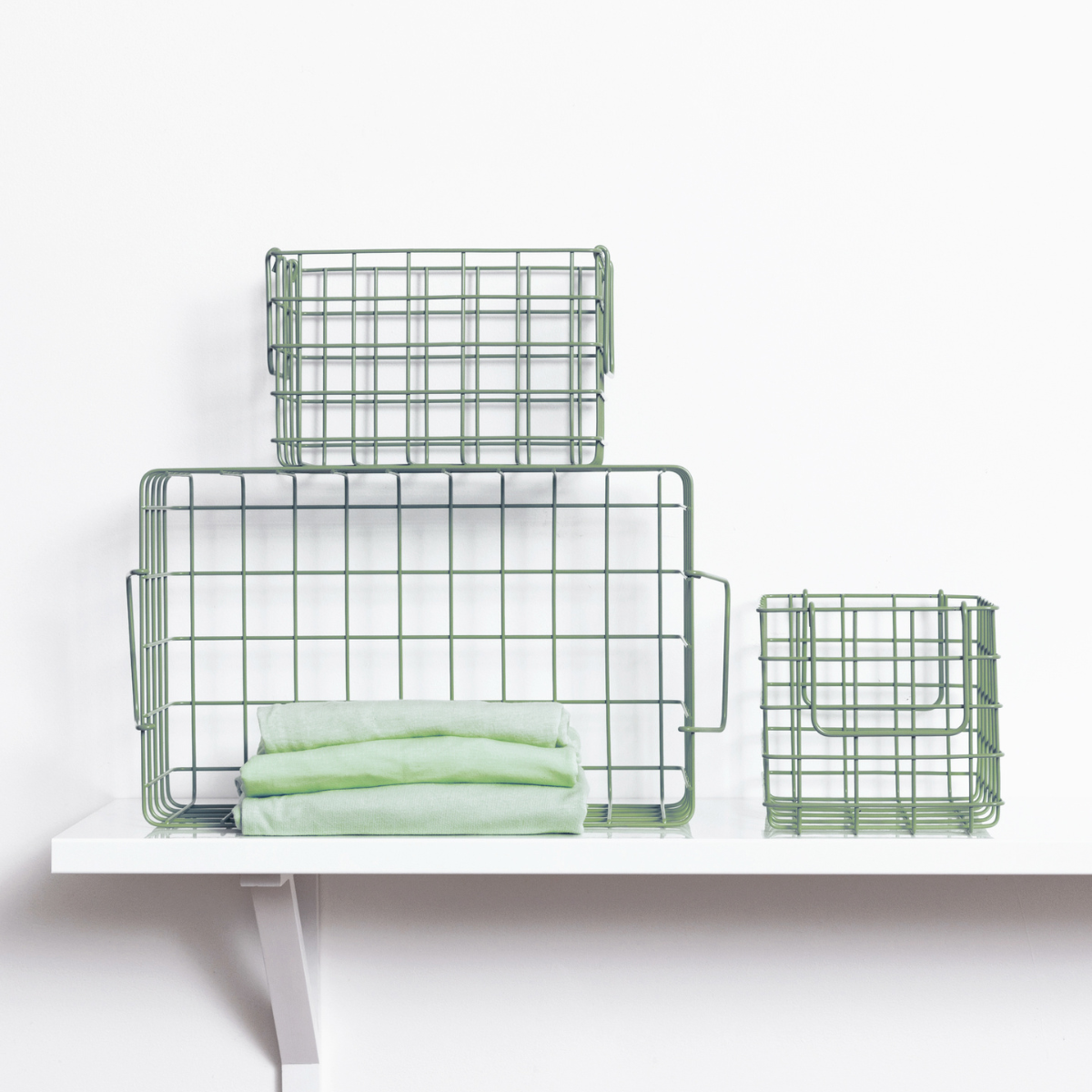 Set of green wire baskets on a white surface with a white background