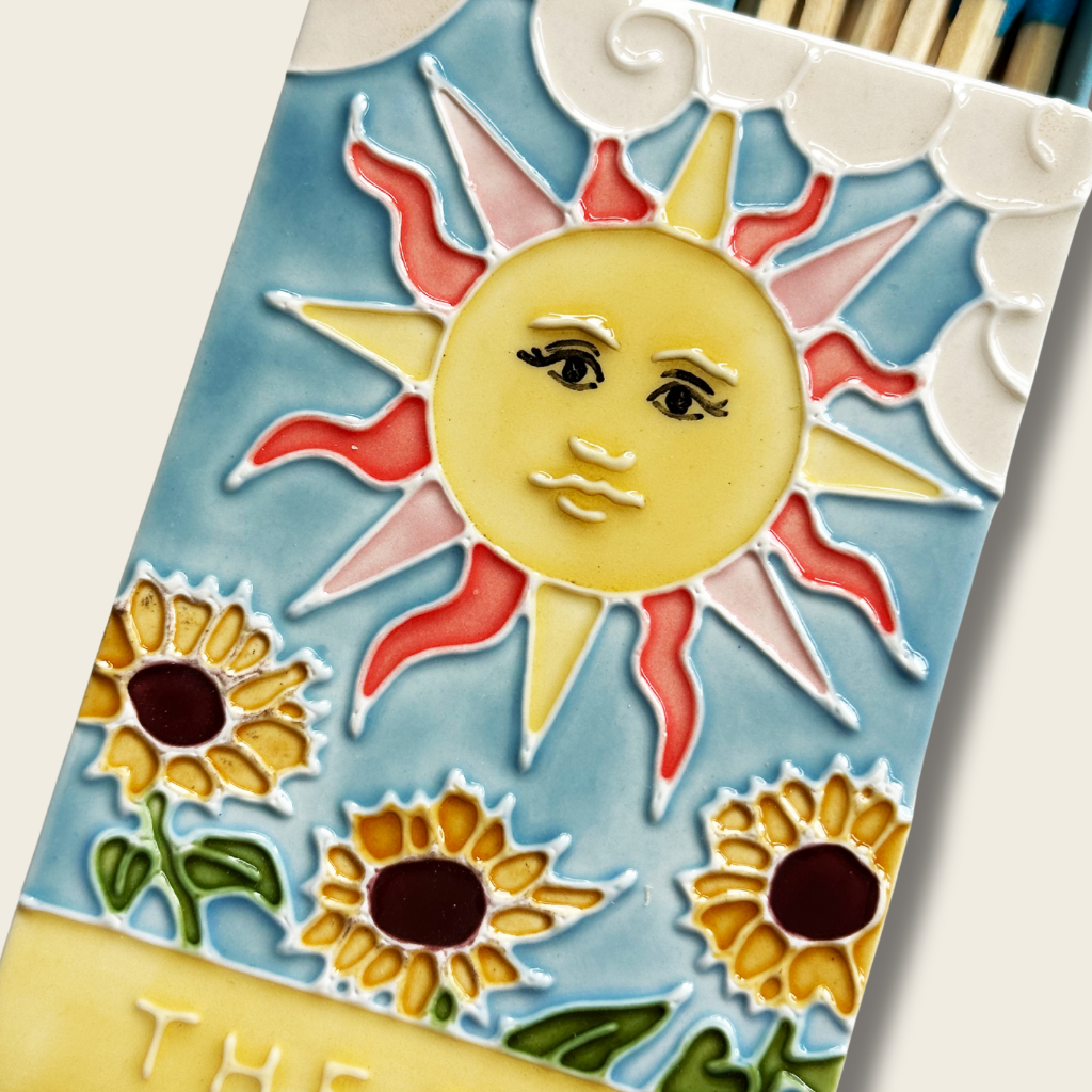 Decorative tile with sun and sunflower design on a blue background