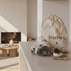 Product set with 'treowe' branded bag and items on a wooden surface against a brick wall.