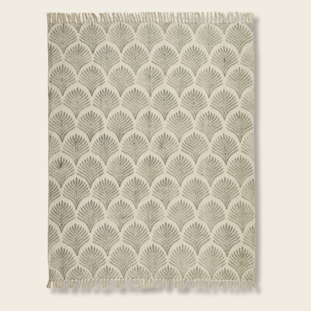 Textile with leaf pattern and fringe on a plain background